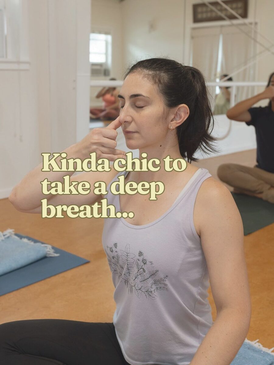 A student practising a breathing technique, eyes closed, fingers at the nose, mid-breath.